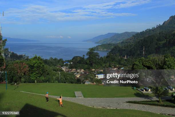 Two children were playing with the view of Lake Toba in front of them. Lake Toba is the largest volcanic lake in Southeast Asia. The lake is located...