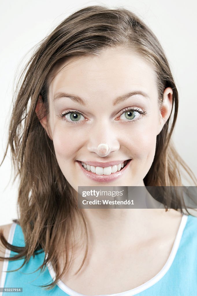 Young woman with cream on her nose, smiling, portrait