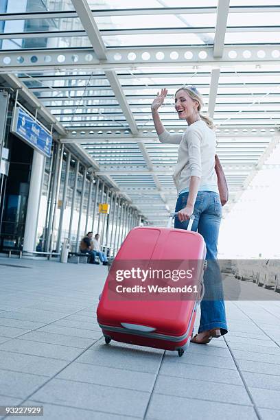 germany, leipzig-halle, airport, young woman with suitcase, waving - woman waving goodbye photos et images de collection