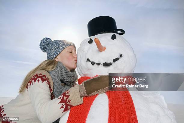 germany, bavaria, munich, young woman kissing snowman, portrait - frau schneemann stock-fotos und bilder