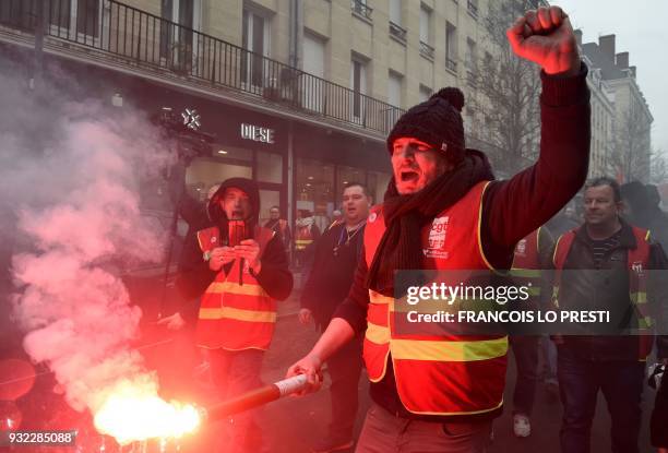 Protester raises his fist holding a flare during a march on March 15, 2018 in the French northern city of Valenciennes, during a demonstration called...