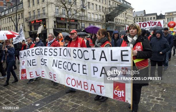 People march behind a banner reading "We don't negociate the social regression, we're fighting it" on March 15, 2018 in the French northern city of...