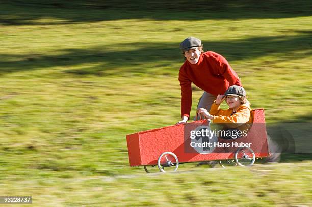 austria, salzburger land, man and boy (12-13) with soapbox car, having fun - soapbox cart stock pictures, royalty-free photos & images