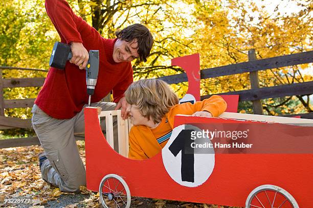 austria, salzburger land, young man fixing soapbox car, boy (12-13) watching - soapbox cart stock pictures, royalty-free photos & images