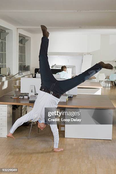 germany, munich, businessmen in office, one of them doing cartwheel - cartwheel stockfoto's en -beelden