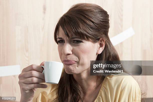 germany, cologne, young woman holding cup of coffee, portrait - offensive stock-fotos und bilder