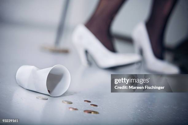 germany, plastic cup and coins on floor, person in background, low section - mareen fischinger foto e immagini stock