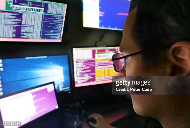 man wearing glasses looking at computer screens - multiple screens stockfoto's en -beelden