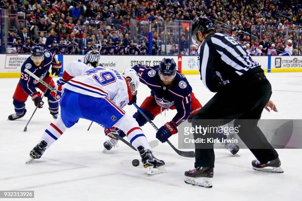 Linesman Pierre Racicot drops the puck for Logan Shaw of the Montreal Canadiens and Brandon Dubinsky of the Columbus Blue Jackets during the game on...