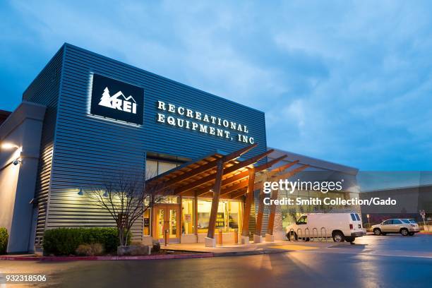 Illuminated facade at dusk with logo and sign at the Recreational Equipment Inc sports and outdoors equipment store in Dublin, California, March 12,...