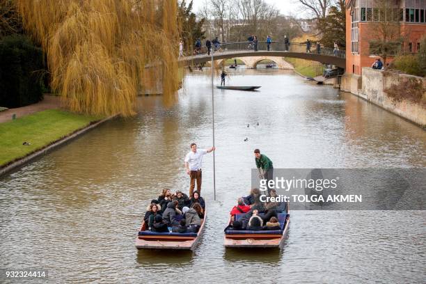 Punt operators take customers on chauffeured punting trips along the River Cam in Cambridge, east of England, on March 14, 2018. / AFP PHOTO / Tolga...