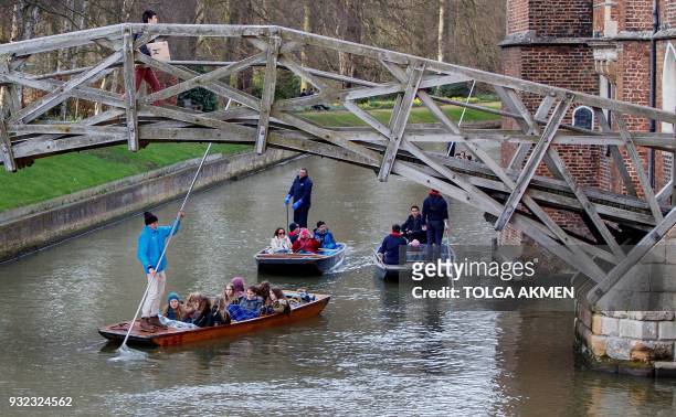 Punt operators take customers on chauffeured punting trips along the River Cam in Cambridge, east of England, on March 14, 2018. / AFP PHOTO / Tolga...