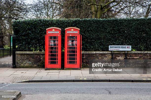 red twin telephone booths in the city of london close to hyde park. - lugar famoso internacional fotografías e imágenes de stock