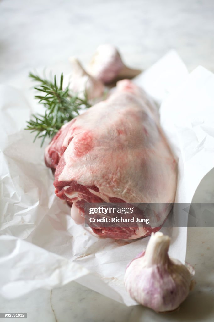 Fresh leg of lamb on white butcher paper still life.