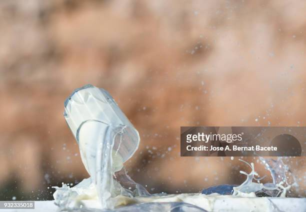 impact of a glass of crystal with milk that falls down on the soil. spain - exploding glass stockfoto's en -beelden