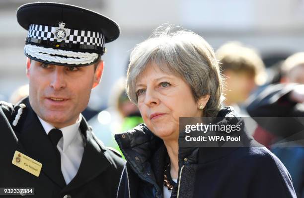 British Prime Minister Theresa May speaks with an officer as she visits the city where former Russian intelligence officer Sergei Skripal and his...