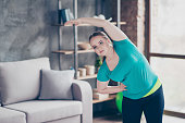 Sport healthy active lifestyle people concept. Fatty cute charming confident chubby concentrated clothed in green tshirt young woman is inclining to side and stretching arms
