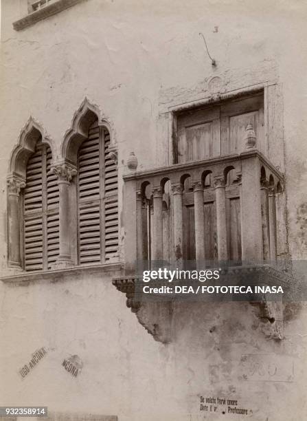 Gothic mullioned window and balcony with campaign posters for Ugo Ancona , Italian teacher and politician, Venzone, Friuli-Venezia Giulia, Italy,...