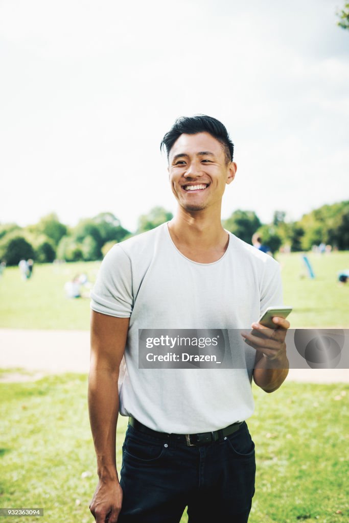 Handsome Chinese guy with smartphone in park