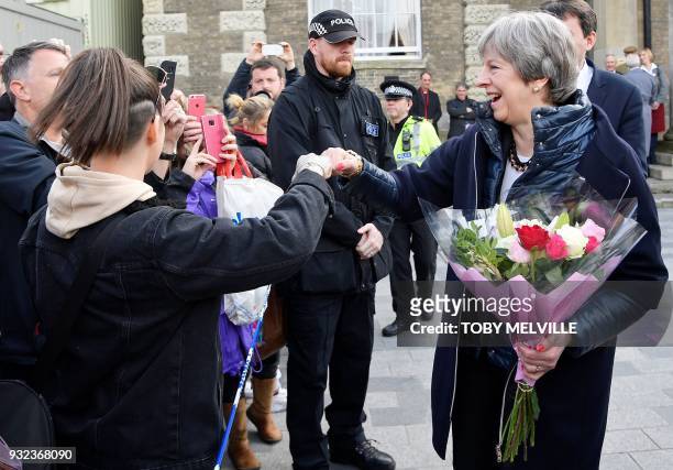 Britain's Prime Minister Theresa May "fist-bumps" a member of the public during her visit to Salisbury, southern England, on March 15 where she...