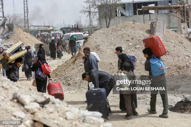 Syrians civilians evacuated from the Eastern Ghouta enclave pass with belongings through the regime-controlled corridor opened by government forces...