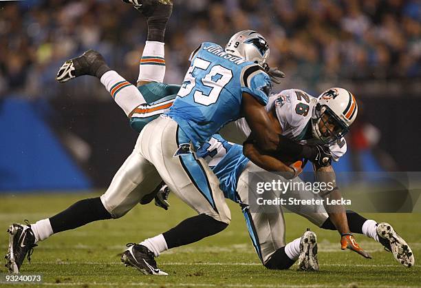 Lex Hilliard of the Carolina Panthers is tackled by against Landon Johnson and Richard Marshall of the Miami Dolphins at Bank of America Stadium on...