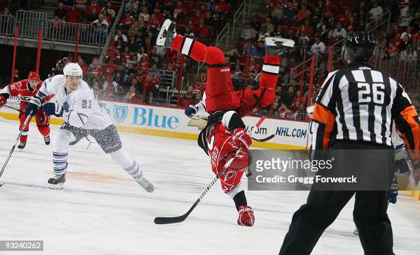 Erik Cole of the Carolina Hurricanes gets upended by Ian White of the Toronto Maple Leafs during a NHL game on November 15, 2009 at RBC Center in...