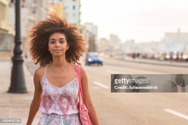 Portrait of pretty young woman walking on Malecon, Havana at dusk