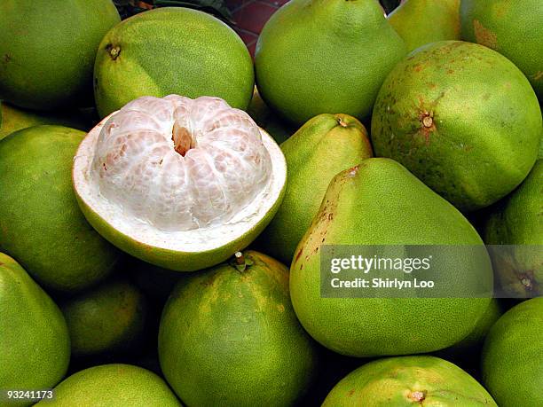 half peeled pomelo on top of a stack of pomelos - pummelo stock pictures, royalty-free photos & images