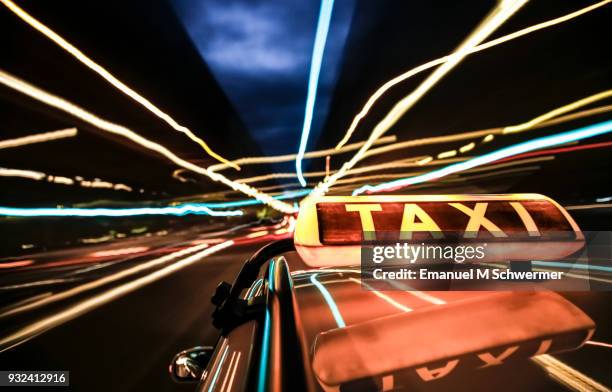 taxi drives through the city of berlin - taxi sign prominent in foreground - taxi van stockfoto's en -beelden