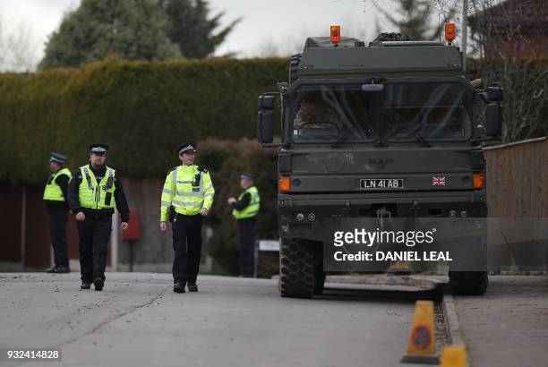 British police officers stand on duty as members of the Army work in a residential street in Alderholt, southern England, on March 15 as...