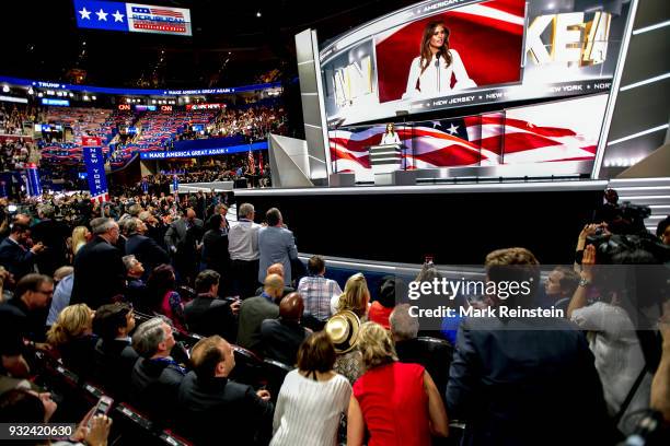 With a massive image projected above her, former model Melania Trump speaks from the podium on first night of Republican National Convention at...