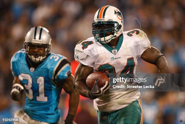 Ricky Williams of the Miami Dolphins runs away from Richard Marshall of the Carolina Panthers during their game at Bank of America Stadium on...