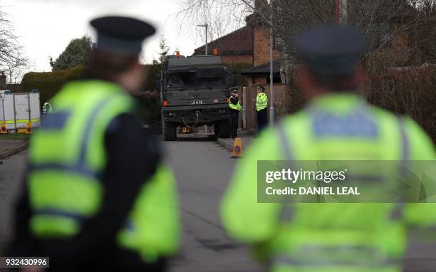 British police officers stand on duty as members of the Army work in a residential street in Alderholt, southern England, on March 15 as...