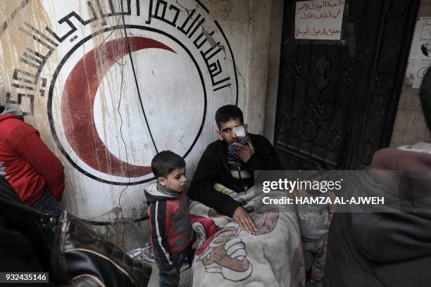 Wounded Syrian man sits before a mural on a wall bearing the logo of the Syrian Arab Red Crescent at the organisation's branch in the rebel-held town...