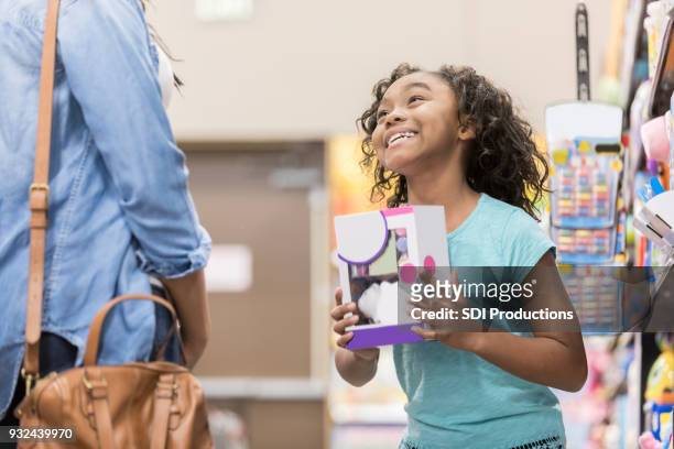 little girl pleads for mom to buy her a toy - indulgence stock pictures, royalty-free photos & images