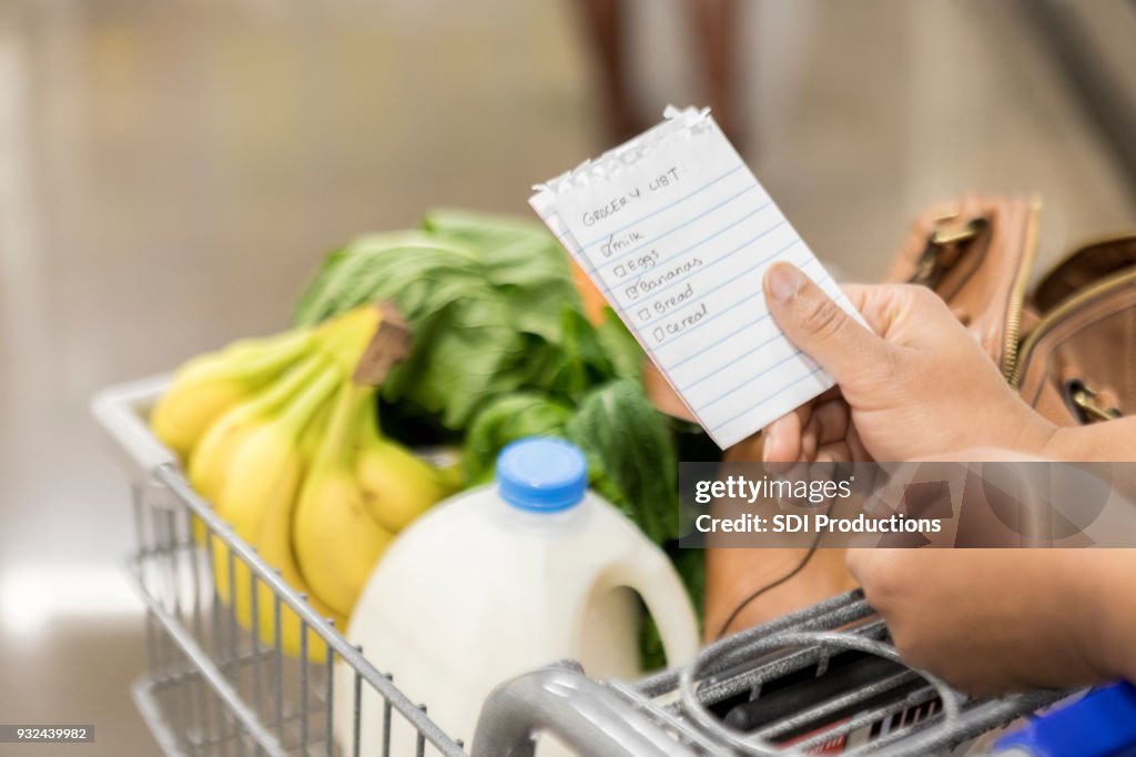 Mujer irreconocible comprueba elementos de lista de la compra