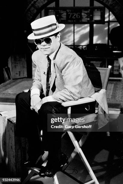 Portrait of English Pop musician Elton John as he sits in a chair at MTV Studios, New York, New York, May 11, 1983.