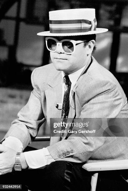 Portrait of English Pop musician Elton John as he sits in a chair at MTV Studios, New York, New York, May 11, 1983.