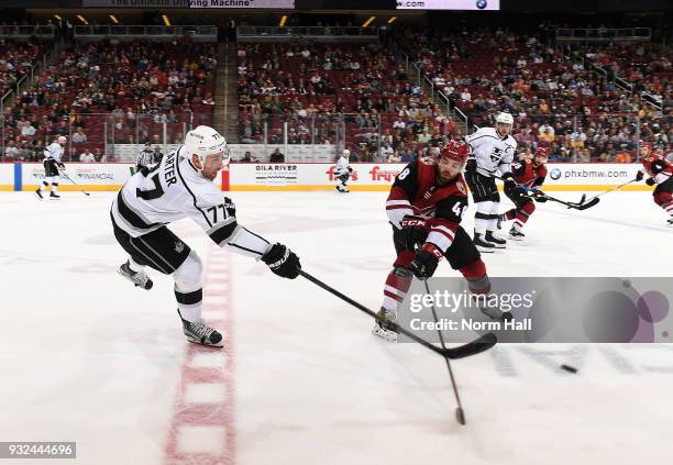 Jordan Martinook of the Arizona Coyotes attempts to knock the puck away from Jeff Carter of the Los Angeles Kings at Gila River Arena on March 13,...