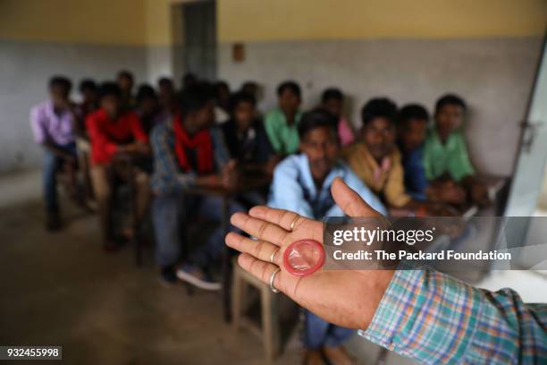 Trainer from Pathfinder International demonstrates condom use for safe sex and pregnancy prevention to adolescent boys at the village school. These...