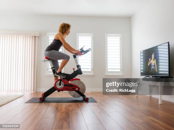 donna che si allena su spin bike in casa - pinning foto e immagini stock