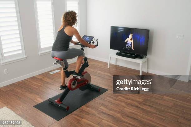woman exercising on spin bike in home - peloton stock pictures, royalty-free photos & images
