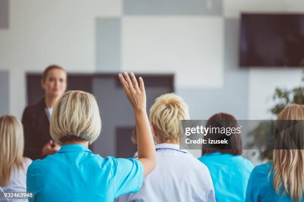 woman giving a speech on seminar for medical staff - large group of people raising hands stock pictures, royalty-free photos & images