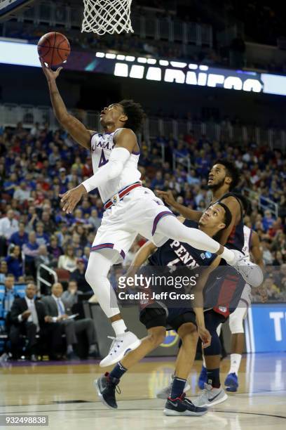 Devonte' Graham of the Kansas Jayhawks attempts a shot past Darnell Foreman of the Pennsylvania Quakers in the second half during the first round of...
