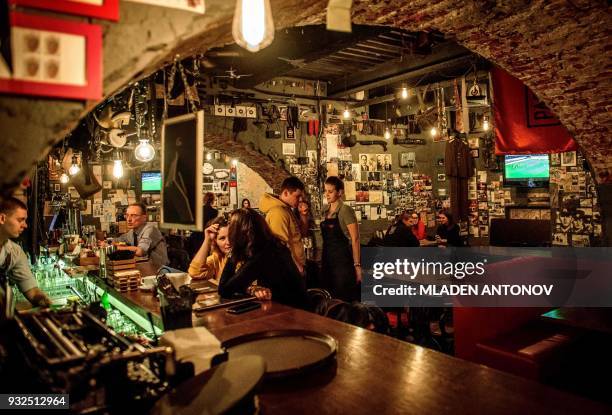 Patrons enjoy drinks at the "Intelligence" spy themed bar near the famous KGB and current FSB building on Lubyanka square in Moscow on March 15,...