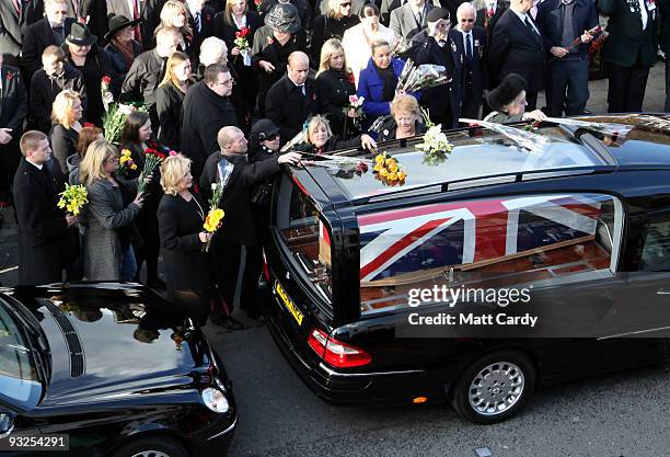 The family of corporal Loren Marlton-Thomas place flowers on the roof of the hearse carrying his coffin as it passes mourners lining the High Street...