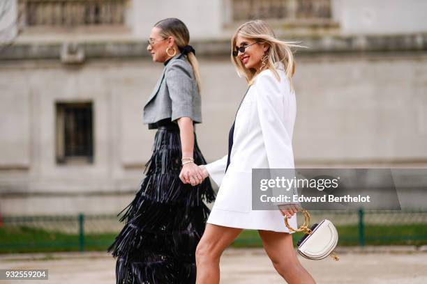 Guest wears sunglasses, large creole earrings, a grey prince-of-wales checkered bolero jacket, a black fringe skirt ; a guest wears sunglasses, large...