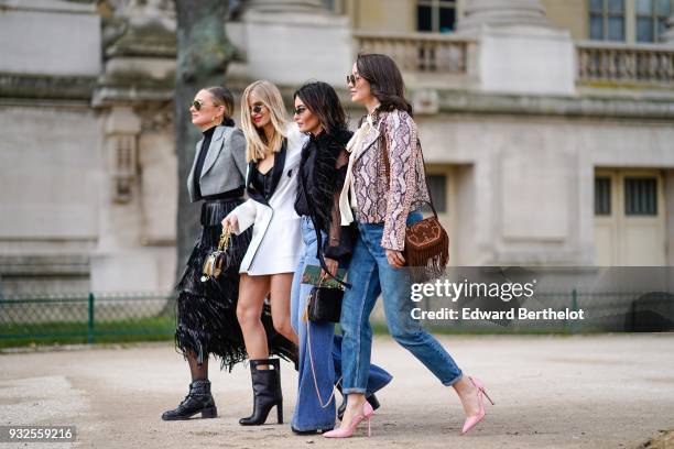 Guest wears sunglasses, large creole earrings, a grey prince-of-wales checkered bolero jacket, a fringe skirt, black booties ; a guest wears...