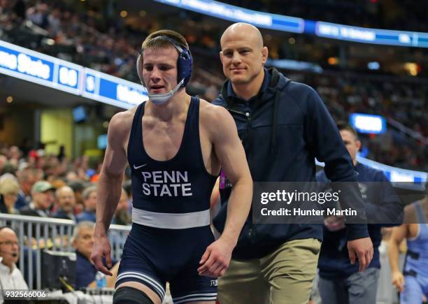 Jason Nolf of the Penn State Nittany Lions walks off the mat with head coach Cael Sanderson after winning his match during session one of the NCAA...